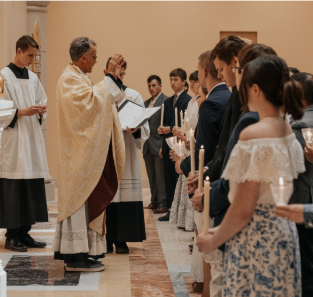 Students attending a community service while holding candles.